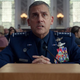 A scene from Space Force starring Steve Carrell sitting in front of a desk.